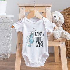 Daddy's Little Caddy Baby Bodysuit Bodysuit is 100% cotton.  We design & print our products with care & love! We use the best quality vinyls, inks & transfers on all products. * * * * * * * * * * * * * * * * * * * * * * * * * * * * * SHIPPING: We want to get your product to you as quickly as possible, your purchase will be shipped through Australia post, Express post is available for selection. * * * * * * * * * * * * * * * * * * * * * * * * * * * * * GUARANTEE: We stand behind our products with a 100% guarantee; if you are unsatisfied with our product, please let us know & we will rectify any issues. We are unable to refund products due to change of mind or those that are personalised. Casual Cotton Bodysuit As Gift, Family Matching Cotton Onesie For Birthday, White Cotton Onesie As A Gift, Fitted Cotton Onesie As A Gift, Fitted Cotton Bodysuit For Gender Reveal, White Cotton Family Matching Onesie, Cotton Letter Print Bodysuit As Gift, Unisex Cotton Onesie For Gender Reveal, Cotton Onesie With Letter Print For Gender Reveal