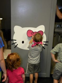 two children are playing with a hello kitty wall decal on the door to an office