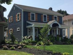 a blue house with shutters on the windows and flowers in the front garden area