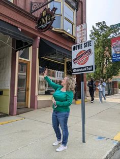 a woman standing next to a movie site sign