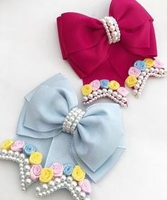 two bows with flowers and pearls on them are laying next to each other in different colors