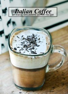 a glass mug filled with liquid and chocolate shavings on top of a wooden table