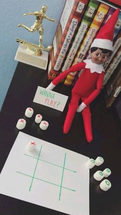 an elf is playing tic - tac toe on the table next to some books