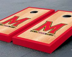 two red cornhole game boards with m on them