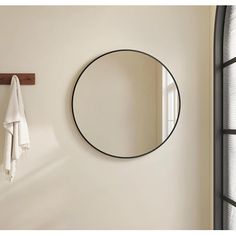 a round mirror hanging on the wall next to a towel rack