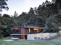 a car is parked in front of a modern house with stone walls and large windows