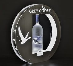 a bottle of grey goose vodka is displayed in front of a circular sign with an image of a bird on it