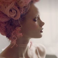 a woman with pink hair is looking off into the distance