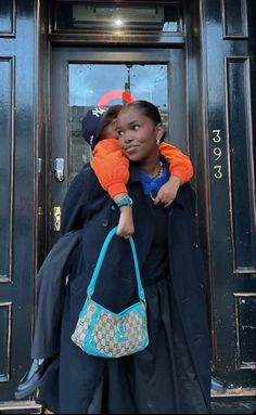 a woman holding a small child in her arms while standing next to a black door