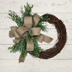 a wreath with burlock and greenery tied to it on a white wooden wall