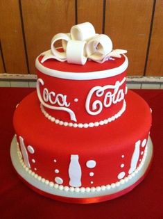 a coca - cola cake on a red tablecloth with white frosting and bows