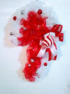 a red and white christmas wreath with ornaments on the front, attached to a wall