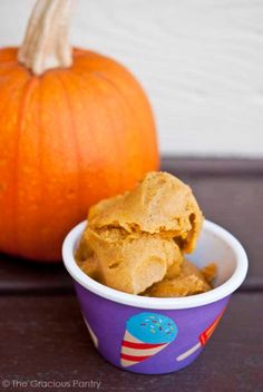 a bowl filled with peanut butter next to an orange pumpkin