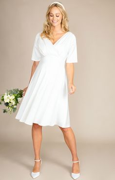 The Zoey maternity wedding dress is simple, refined and elegant.Heavyweight sheen satin has a gentle stretch making it sumptuous and comfortable to wear all day (and night) long. A cross over neckline features dramatic pleats from shoulder to waist. Elbow length sleeves and a knee length skirt create a fun and flirty finish to this sweet bridal style you will love. Add a touch of sparkle with one of our many decorative bridal sashes or choose a beautiful headband for playful glamour. Cross-over Elegant White Maternity Wedding Dress, Elegant White Maternity Bridesmaid Dress, Fitted Empire Waist Maternity Dress For Wedding, White Wedding Dress With Flattering Silhouette, Elegant Empire Waist Dress For Wedding Night, Fitted V-neck Maternity Bridesmaid Dress, Elegant V-neck Maternity Dress For Evening, Elegant White Maternity Dress With V-neck, Elegant White V-neck Maternity Dress