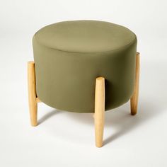 a green ottoman with wooden legs on a white background in the shape of a footstool