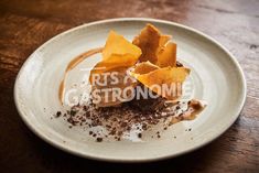 a white plate topped with dessert and toppings on top of a wooden table next to a cup