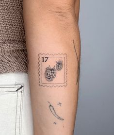 a person with a tattoo on their arm holding a postage stamp that has two pineapples on it