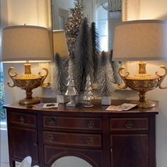 two lamps are sitting on top of a wooden table next to a mirror and christmas tree