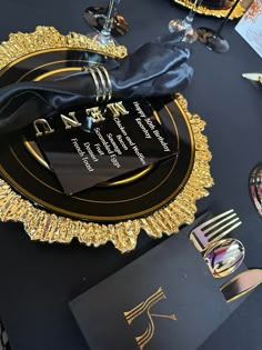 a black and gold table setting with plates, napkins and silverware on it