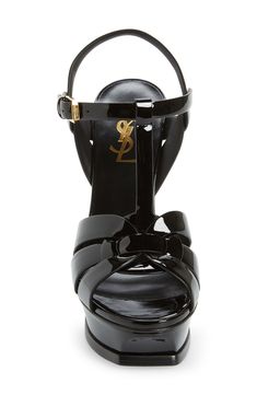 An icon since it first debuted on the runway, Saint Laurent's stylishly strappy Tribute sandal is lifted by a soaring tapered heel and beveled platform sole. 5" (127mm) heel; 1 1/4" platform (size 38.5) Adjustable ankle strap with buckle closure Leather upper, lining and sole Made in Italy Women's Designer Shoes Luxury T-strap Heels For Summer, Evening T-strap Platform Sandals, Luxury Black T-strap Sandals, Luxury High Heel T-strap Sandals For Party, Luxury T-strap Sandals With Ankle Strap For Party, Evening T-strap Sandals With Heel Loop, Luxury Ankle Strap T-strap Sandals For Evening, Luxury Black T-strap Heels, Luxury Evening T-strap Sandals With Ankle Strap