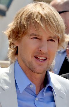 a close up of a person wearing a suit and tie with other people in the background