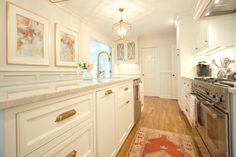 a kitchen with white cabinets and gold trim on the doors, windows, and drawers