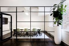 an office with glass walls and wooden flooring, white vases on the table