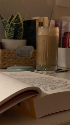 an open book sitting on top of a desk next to a cup of coffee and books