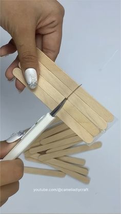 a person is cutting wood strips with a pair of scissors