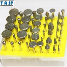 many different sizes and shapes of screws in a plastic container on a yellow surface