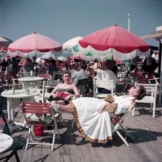 a woman laying on top of a wooden floor next to tables covered in umbrellas