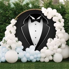 a tuxedo backdrop with balloons and greenery