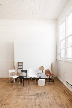 four chairs are arranged in a room with white walls and wood flooring on the side