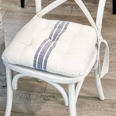 a white chair with a blue and white striped seat cushion on it's back