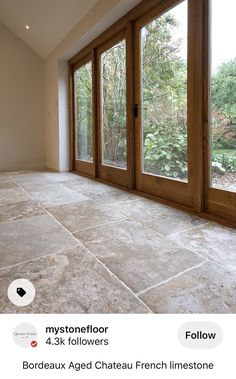 an empty room with large windows and stone flooring is shown in this postcard