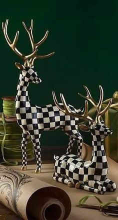 two deer figurines sitting on top of a table next to thread spools