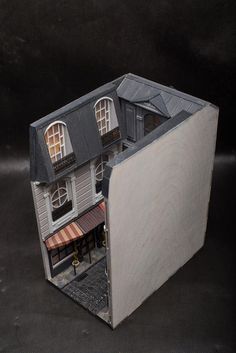 a model house with an open door and two windows on the top floor, in front of a black background