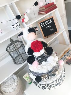 a stuffed cow sitting on top of a pile of diapers next to a book shelf