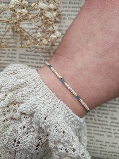 a woman's arm with a bracelet on top of it next to a flower