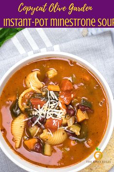 two bowls filled with pasta and vegetable soup on top of a white cloth next to bread