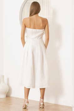 A chic strapless midi white linen dress with charming rose accents adorning the bodice, featuring invisible zippers and convenient pockets. Perfect for effortless summer style! LENGTH: Top of shoulder to hem 42" FABRICATION: 100% LINEN STYLE#. DR-21282 WHITE LINEN- WHITE *Dry Clean or wash on cold and hang flat to dry *Model is wearing size XS White Strapless Dress For Brunch With Straight Neckline, White Linen Midi Dress With Straight Neckline, Chic White Strapless Dress For Garden Party, Strapless Summer Dresses With Pockets, Chic White Linen Dress For Garden Party, White Linen Dress With Straight Neckline For Summer, Strapless Linen Summer Dress, Strapless Linen Dress For Spring, Summer Strapless Linen Dress