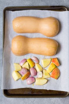 squash, onions and potatoes on a baking sheet ready to be cooked in the oven