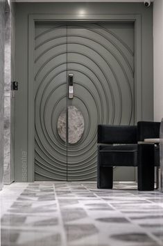 a black chair sitting in front of a door with a circular design on the wall