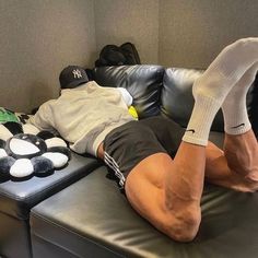 a man laying on top of a black leather couch next to a pile of stuffed animals