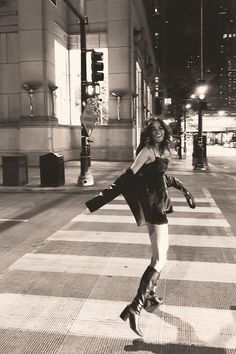 a woman is crossing the street at night