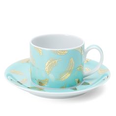 a blue cup and saucer with gold leaves on it