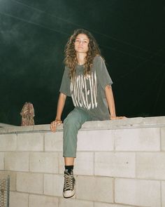 a woman sitting on top of a brick wall