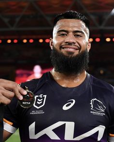 a man with a beard holding a medal in his right hand and smiling at the camera