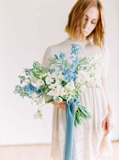 a woman holding a bouquet of blue and white flowers