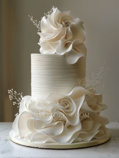 a three tiered white wedding cake with flowers on top